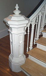 large newel post, white in color, with panels and detail